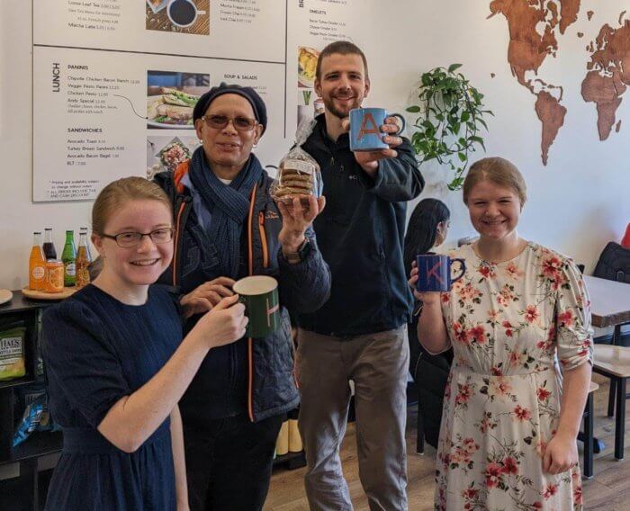 Way Cafe owner Michael Weaver (center right) and two employees pose with mugs gifted to them by a customer (center left).