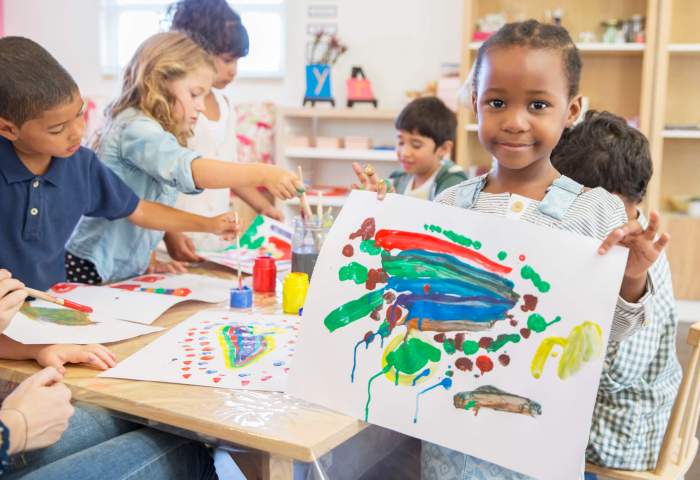 Student showing off finger painting in classroom.