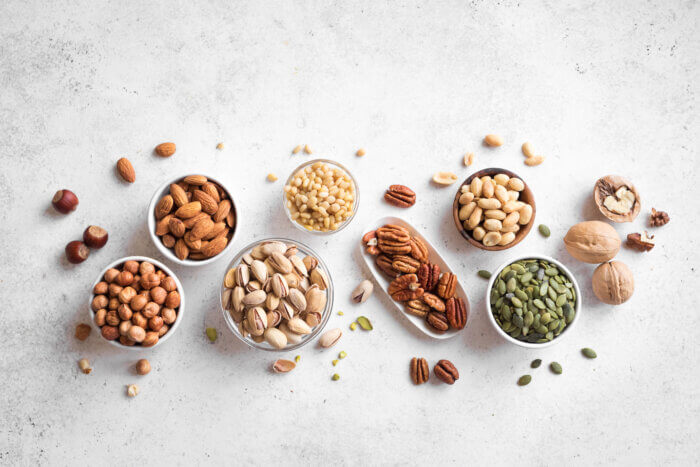 Various Nuts in tiny bowls - pecans, hazelnuts, walnuts, pistachios, almonds, pine nuts, peanuts, pumpkin seeds.