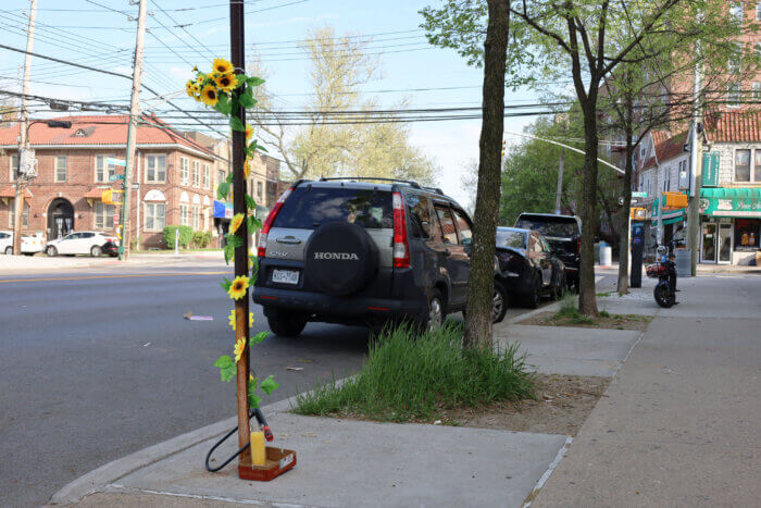 a photo of a pole with a bike lock and flowers around it and a candle in front