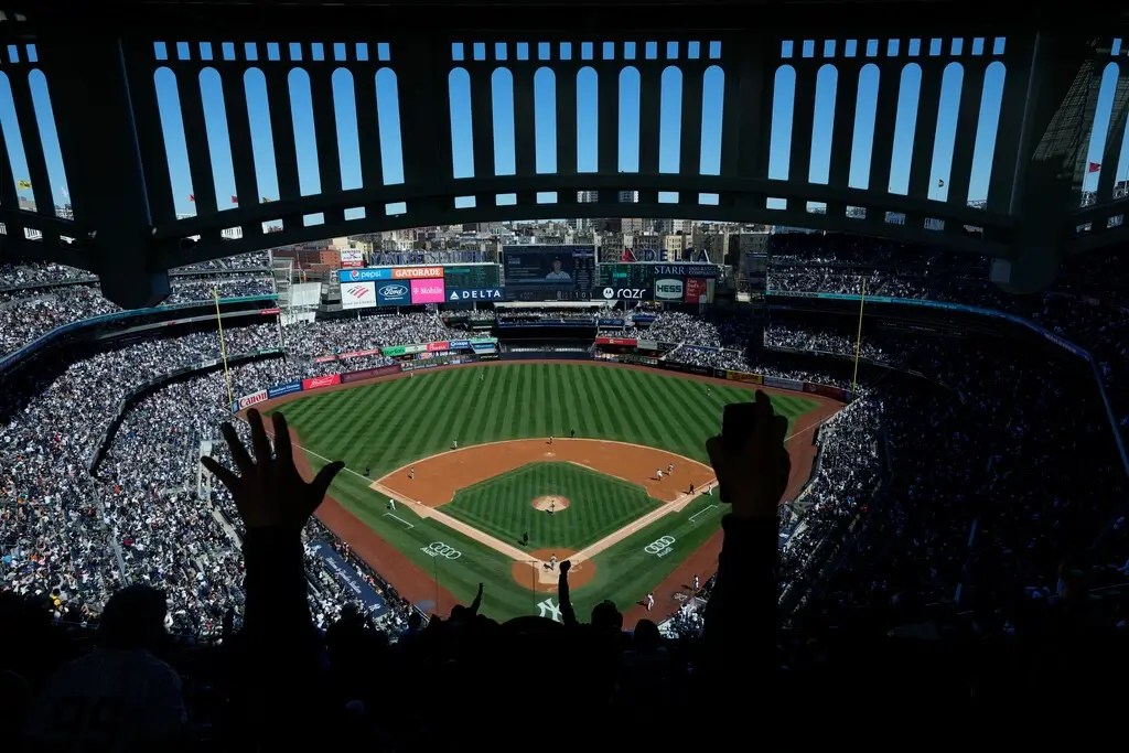 A fan's hands are in the air, cheering at the Yankees game.