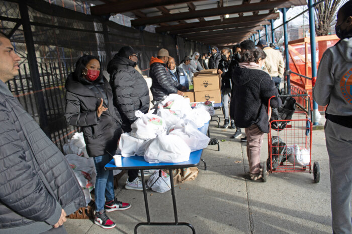 Community members in line receive bags of fresh produce, canned goods, dairy products and more during the Moonshot Nights Community Food Distribution on Saturday, Dec. 9, 2023.