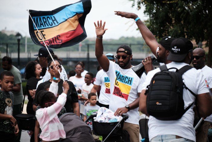 Children wave flags during the March of Dads held by Dad Gang in support of black fatherhood and breaking stereotypes. The march is held in Mill Pond Park on June 29, 2024.